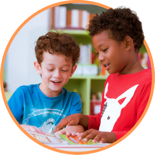 Two young boys reading and pointing at a book together
