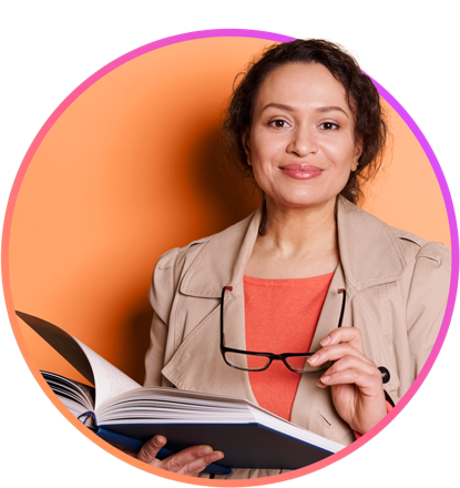 A female educator holding her glasses and a book while smiling at the camera